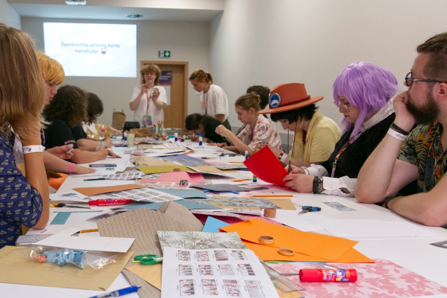 Ludzie przy stole na warsztatach plastycznych patrzący na osobę prawdzącą